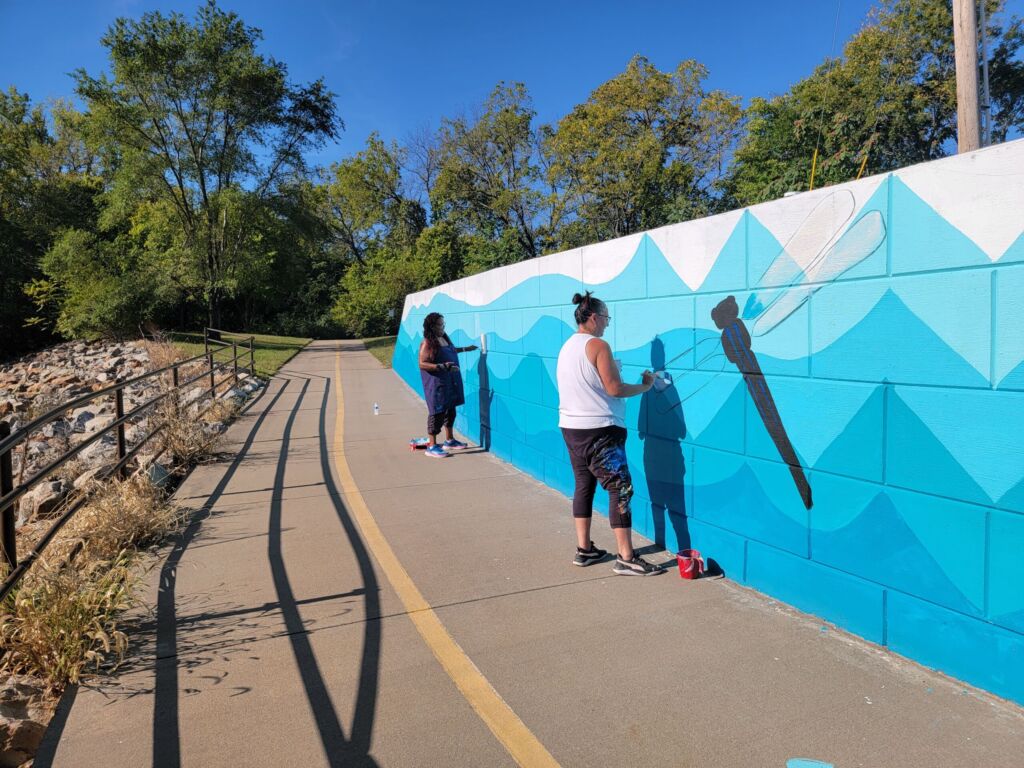 Two individuals painting a mural.
