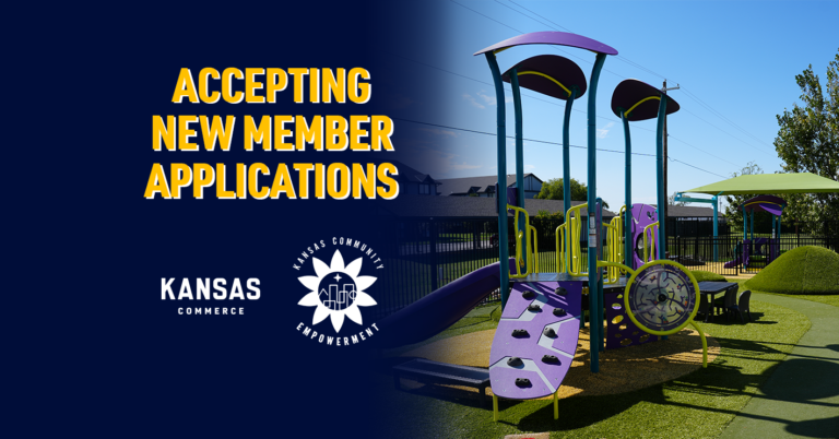 A playground featuring colorful equipment is on the right, including slides and climbing structures. On the left, bold yellow text reads, "Accepting New Member Applications." Below the text are the logos for Kansas Commerce and Angels Community Empowerment.