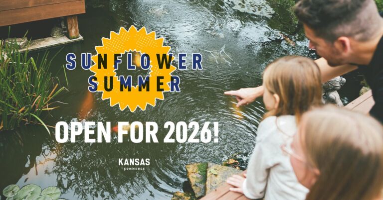 A person points towards a pond with fish, accompanied by another individual. The text reads, "Sunflower Summer Open for 2026!" with "Kansas Commerce" beneath. The scene is serene and outdoors, with greenery and water features.