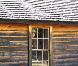 An individual peaks out the window of an old station house.