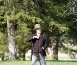An individual in period garb walks on grass.