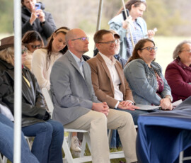 Audience listens to a speaker during an outdoor Pony Express ceremony