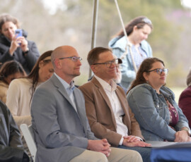 Audience listens to a speaker during an outdoor Pony Express ceremony