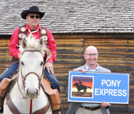 A Pony Express rider, KDOT Sec. Reed pose behind an old station house.