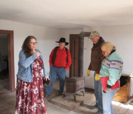 Individuals stand in the room of an old house.